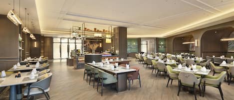 A spacious dining area with multiple tables and chairs, a central bar area, and a view of the kitchen in the background.