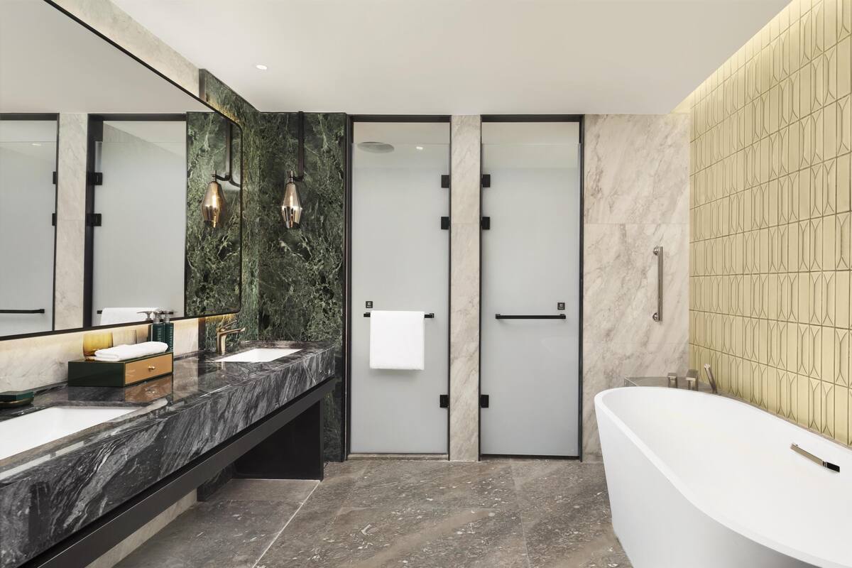 Une salle de bain moderne avec deux lavabos, une grande baignoire et une douche à l’italienne.