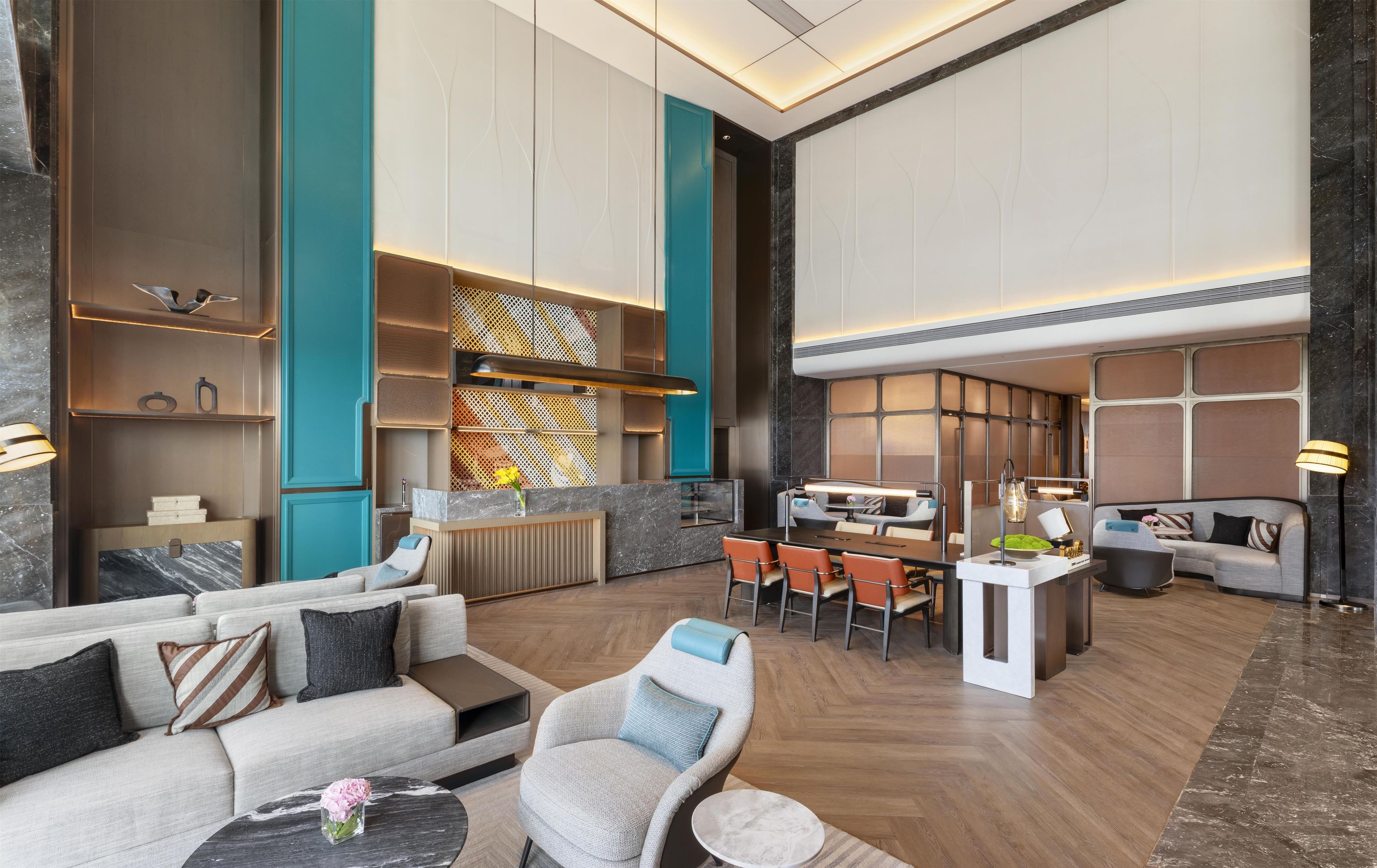 Eine großzügige Hotelhalle mit modernem Design, ausgestattet mit einer Sitzecke mit Sofas und Sesseln, einem Esstisch und einer Rezeption.