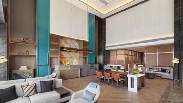 Eine großzügige Hotelhalle mit modernem Design, ausgestattet mit einer Sitzecke mit Sofas und Sesseln, einem Esstisch und einer Rezeption.