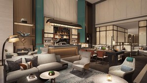 Een moderne hotellobby met een bar, zithoek en een eetruimte.