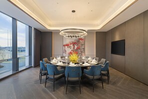 A modern dining room with a round table set for six, large windows, and a city view. - Doubletree by Hilton Zhengzhou Airport Aerotropol (Zhengzhou)