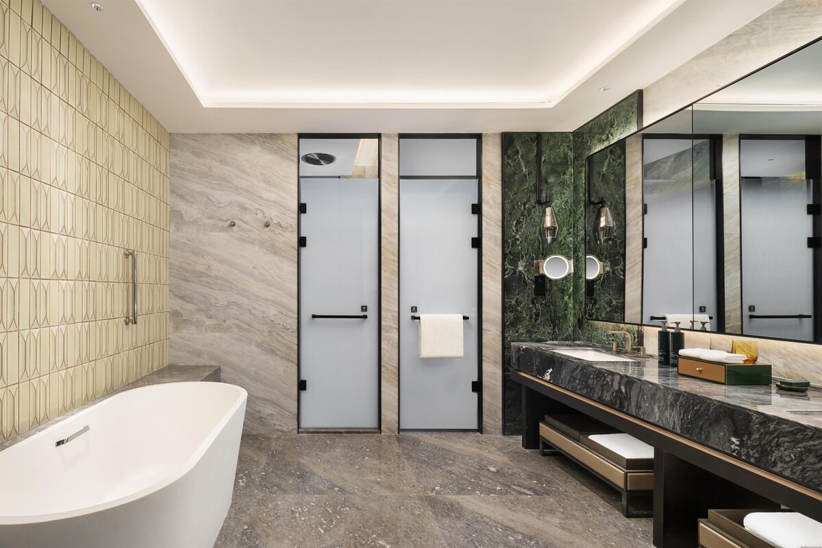 Une salle de bain moderne avec une baignoire sur pieds, un grand miroir et un plan de toilette en marbre.