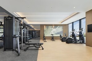Une salle de sport moderne dotée de divers équipements d’exercice, de grandes fenêtres et d’un aménagement spacieux.