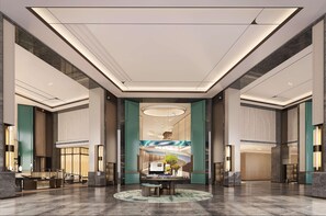 Eine großzügige Lobby mit einer zentralen Rezeption, einem imposanten Kronleuchter und Blick ins Innere durch eine Glaswand.