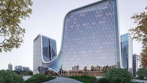 Een modern gebouw met een bijzondere, gebogen gevel, omgeven door groen en een verhard voetpad.