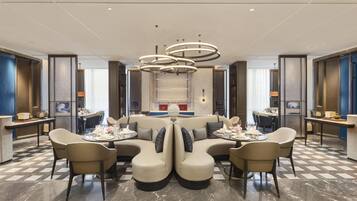 A modern hotel lobby with a central seating area, a staircase, and a view of the city.