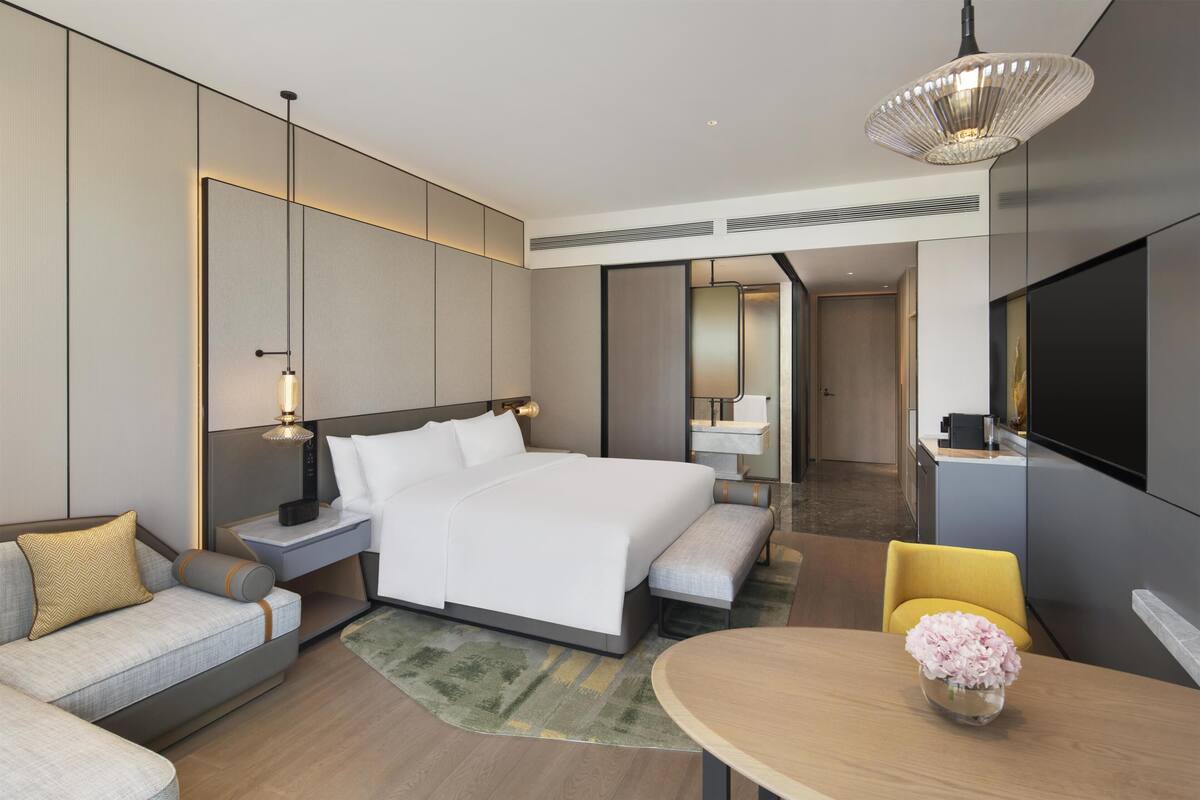 Une chambre d’hôtel moderne dotée d’un grand lit, de tables de chevet, d’un bureau, d’une chaise, d’une télévision et d’un coin repas.