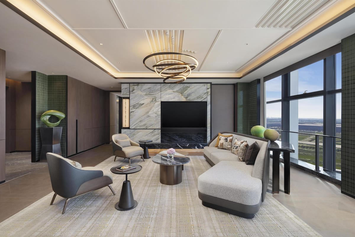 Un salon moderne doté d’une cheminée, de sièges confortables et d’une grande fenêtre offrant une vue sur la ville.