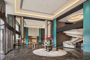 A spacious lobby with a central round table, a staircase, and a modern ceiling design. - Doubletree by Hilton Zhengzhou Airport Aerotropol (Zhengzhou)