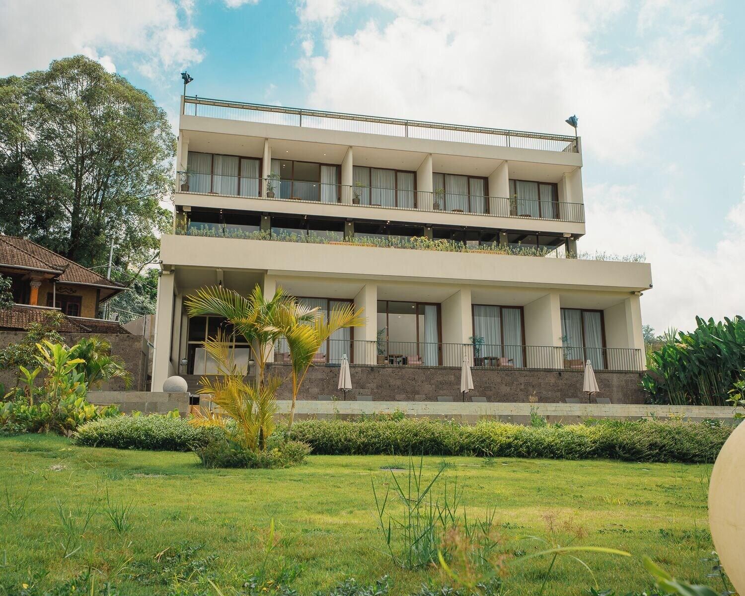 A two-story building with a flat roof, large windows, and a balcony on the upper floor.