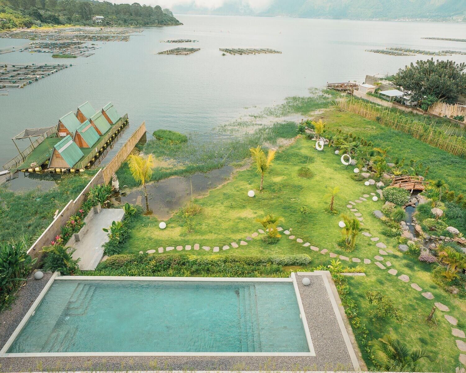 Ein Resort mit Schwimmbad, einem Garten mit einem Gehweg und schwimmenden Strukturen auf dem Wasser.