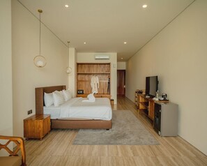 Une chambre d’hôtel moderne avec un grand lit, une télévision, une armoire en bois et une petite kitchenette.
