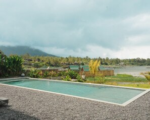A swimming pool with a view of a lake and mountains in the background. - Tribhuwana Padma Resort (Kintamani)