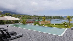 Une piscine dotée de chaises longues et offrant une vue sur un lac et des montagnes.