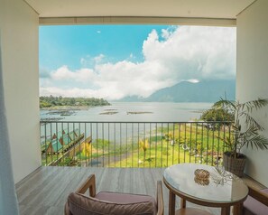 Un balcone con vista su un lago, una zona verdeggiante e una montagna all'orizzonte.