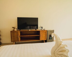 A hotel room with a bed, a wooden cabinet with a television, and a minibar. - Tribhuwana Padma Resort (Kintamani)