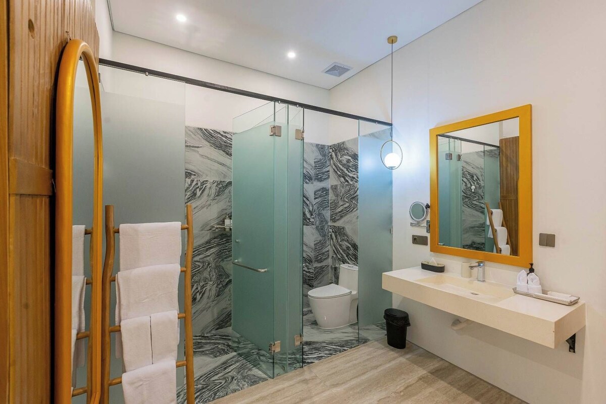 Ein modernes Badezimmer mit Duschkabine aus Glas, einer weißen Toilette und einem Waschtisch mit Spiegel.