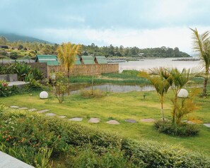 Un jardín tropical con un estanque, palmeras y una valla de madera.
