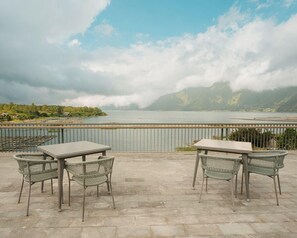 An outdoor seating area with a view of a lake and mountains. - Tribhuwana Padma Resort (Kintamani)