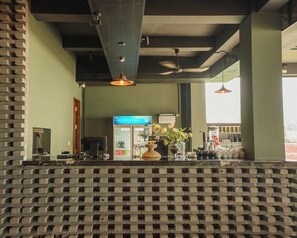 Un'area bar con un bancone, un frigorifero fornito di bevande e un vaso decorativo con fiori.