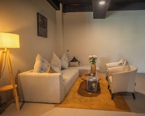 A modern living room with a sofa, armchairs, a coffee table, and a floor lamp. - Tribhuwana Padma Resort (Kintamani)