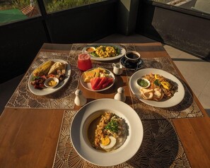 Una tavola apparecchiata con diversi piatti, tra cui uova, verdure e un'insalata di frutta, che suggerisce un'ambientazione da colazione.