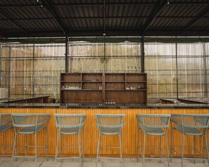Un'area bar con un bancone in legno e sedie in vimini.