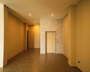Un couloir avec un mur en marbre, une porte et un sol carrelé.