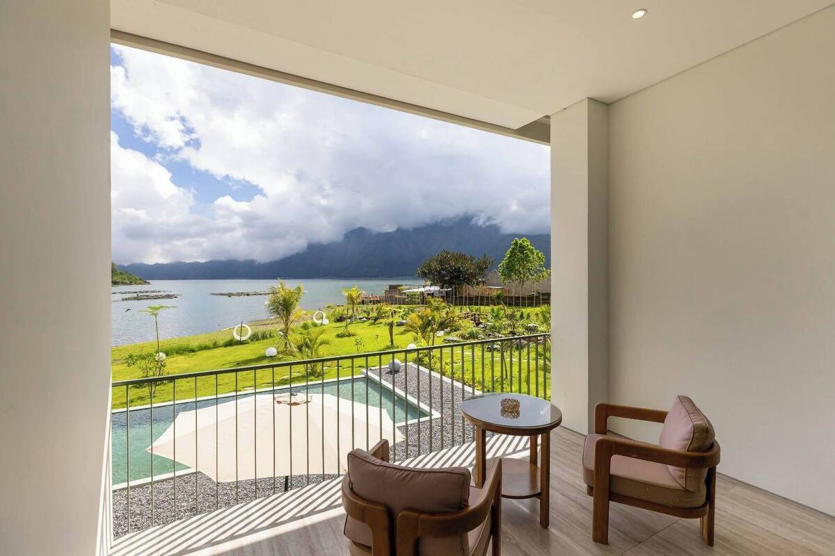 Un balcon donnant sur un lac et des montagnes, aménagé avec deux chaises et une petite table.