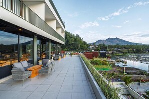 Eine Dachterrasse mit Sitzgelegenheiten im Freien und Blick auf einen Fluss und Berge.