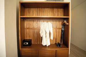 A wooden wardrobe with two drawers, a hanging robe, and a pair of shoes. - Tribhuwana Padma Resort (Kintamani)