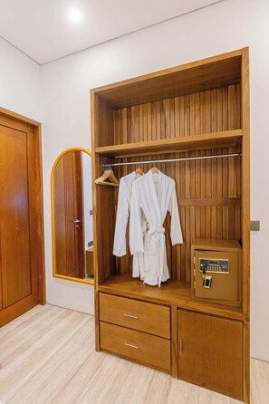 Un armario de madera con dos cajones, una barra para colgar ropa y una caja fuerte pequeña.