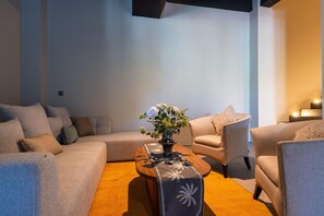 Un salon moderne avec un canapé, un fauteuil et une table basse agrémentée d’un vase de fleurs.