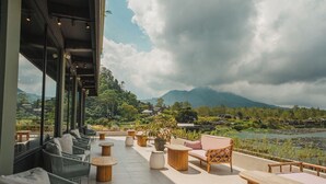 A terrace with outdoor seating, a view of a lake, and a mountainous landscape. - Tribhuwana Padma Resort (Kintamani)