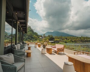 A terrace with outdoor seating, a view of a lake, and a mountainous landscape. - Tribhuwana Padma Resort (Kintamani)
