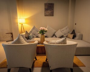 A modern living room with a sofa, two armchairs, a coffee table, a lamp, and a vase with flowers. - Tribhuwana Padma Resort (Kintamani)