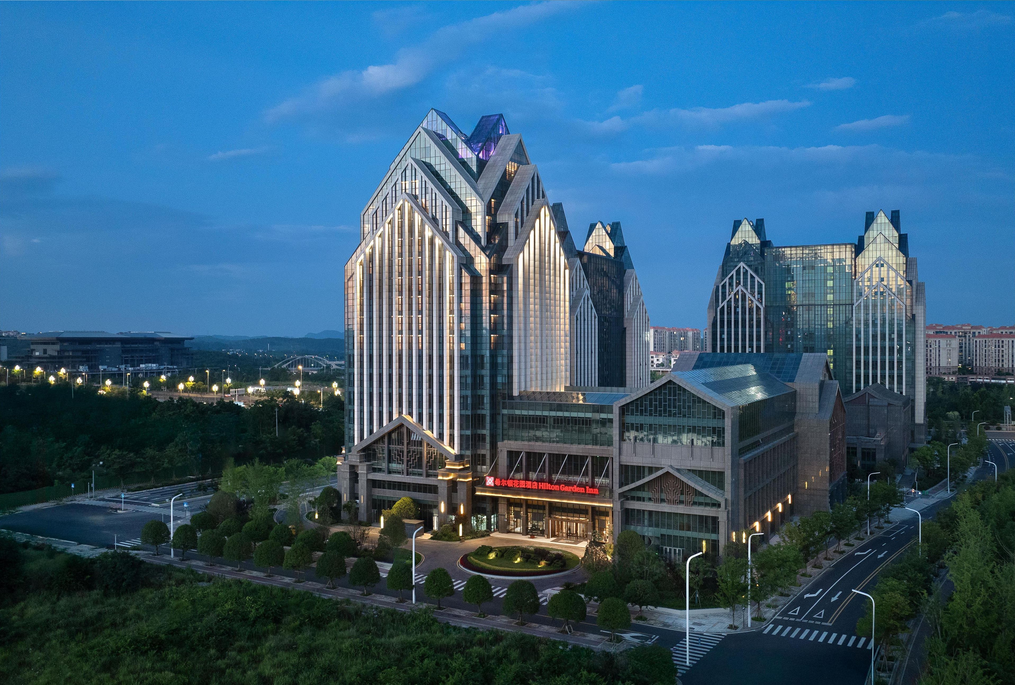 A modern hotel with a distinctive architectural design, featuring a central building with a curved facade and a smaller adjacent structure.
