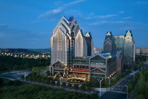 A modern hotel with a distinctive architectural design, featuring a central building with a curved facade and a smaller adjacent structure. - Hilton Garden Inn Guiyang Gui'an New Area (Guiyang)
