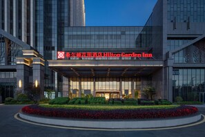 A modern hotel entrance with a large sign for Hilton Garden Inn, featuring a well-maintained garden and a clear sky. - Hilton Garden Inn Guiyang Gui'an New Area (Guiyang)
