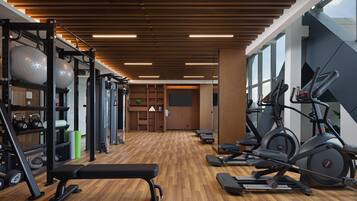 A gym with exercise equipment, a wooden floor, and large windows.