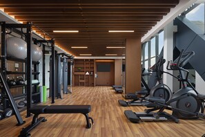 Una palestra con attrezzature per esercizi, un pavimento in legno e ampie finestre.