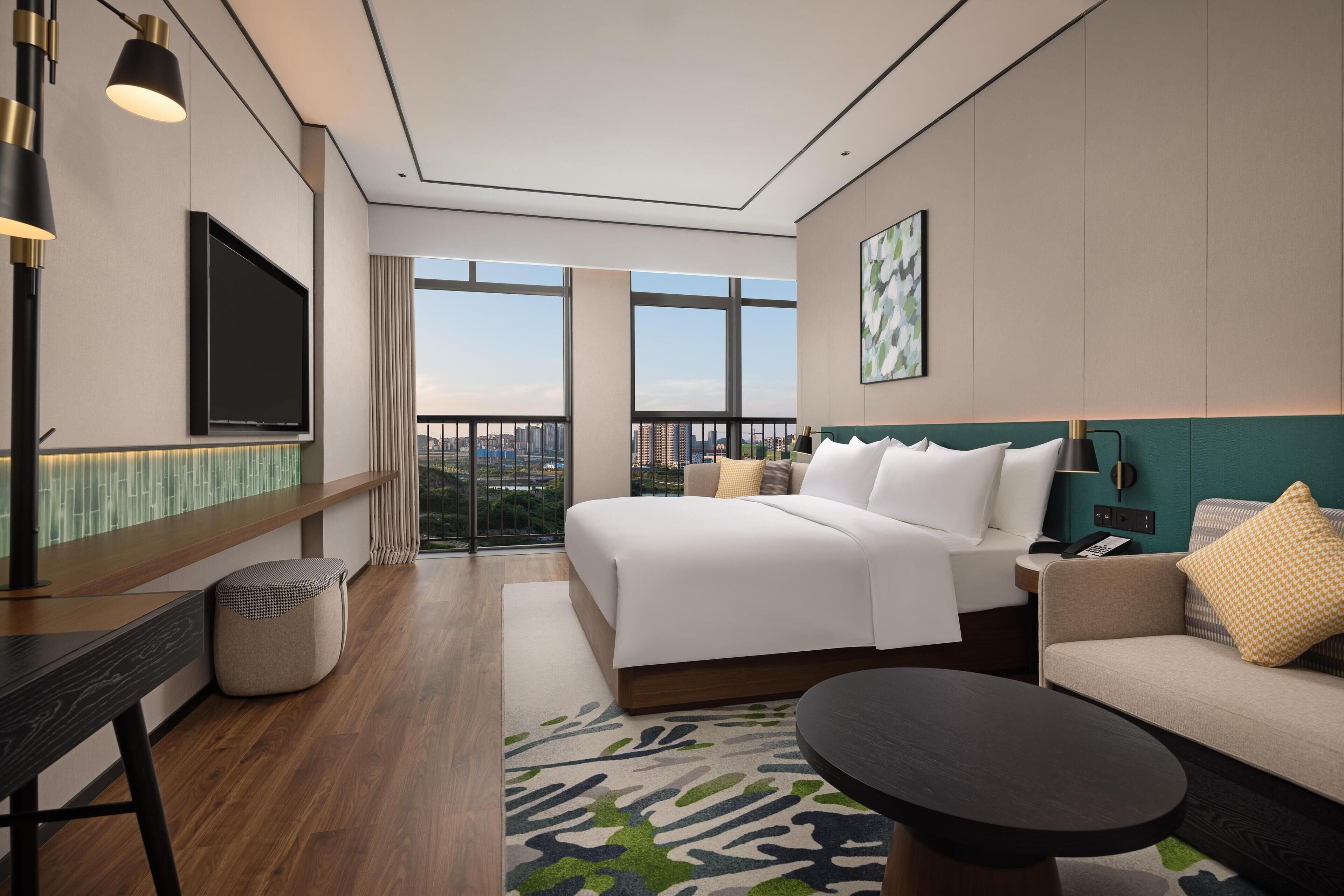 Et moderne hotelværelse med en stor seng, en sofa, et skrivebord og et fjernsyn.