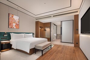 Ett modernt hotellrum med en stor säng, sängbord, en bänk, en tv och en rymlig klädkammare.