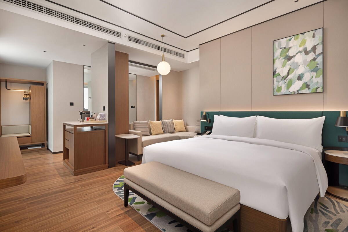 Una camera d'albergo moderna con un letto grande, una scrivania, un’area salotto e un bagno.