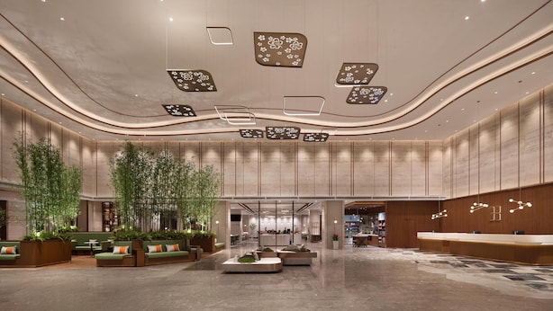 Un lobby espacioso con zonas de estar, un mostrador de recepción y un diseño de techo moderno.