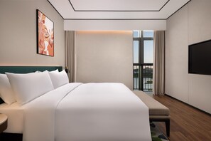 Camera d'albergo con un letto grande, una TV a schermo piatto, una finestra con vista e un quadro appeso al muro.