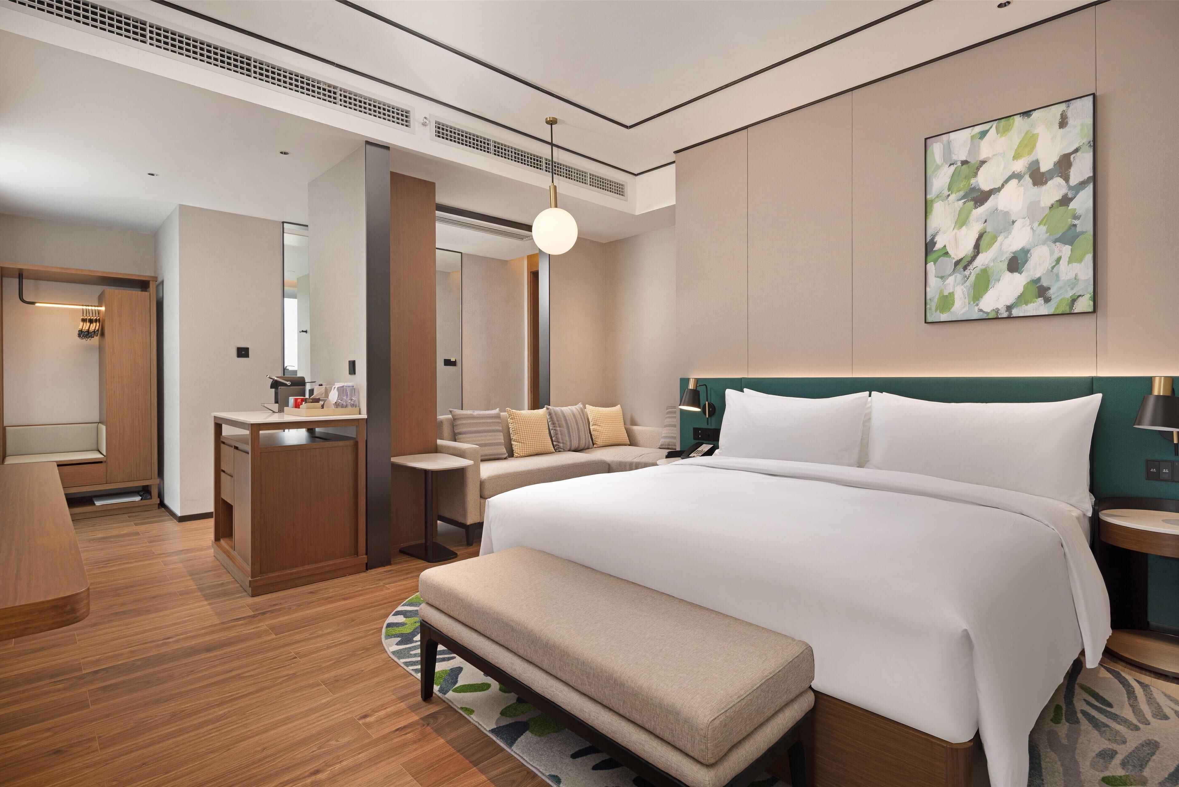 Et moderne hotelværelse med en stor seng, et skrivebord, et siddeområde og et badeværelse.