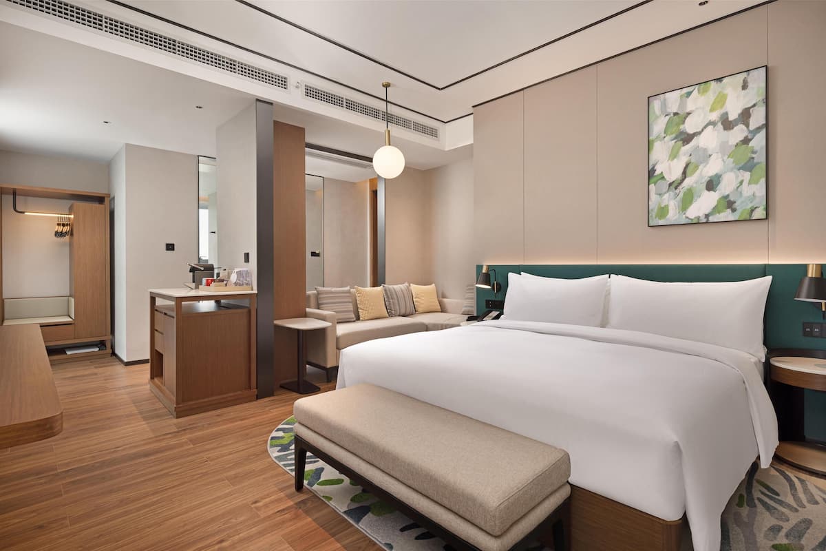 Una camera d'albergo moderna con un letto grande, una scrivania, un’area salotto e un bagno.