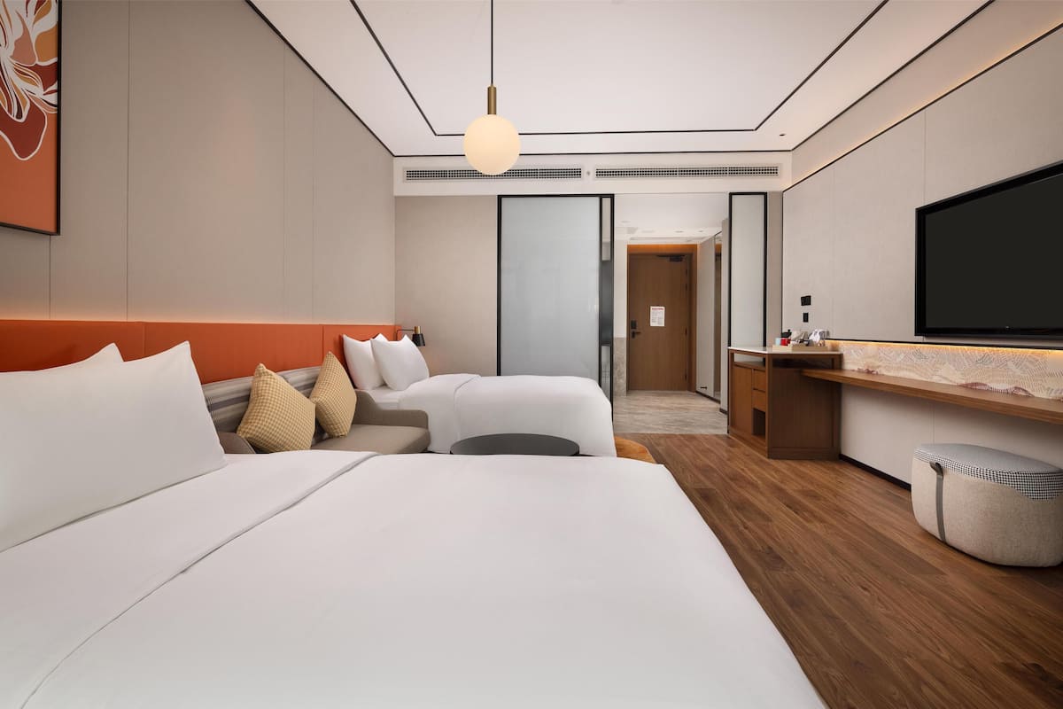 Una camera d'albergo moderna con un letto grande, una scrivania, una televisione e un bagno.